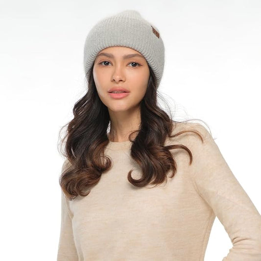 Woman wearing a gray beanie and beige sweater on a white background