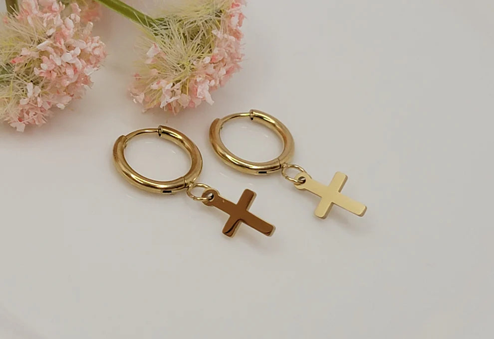 Follow Me Cross Huggie Gold Earrings featuring polished gold huggie hoops with dangling cross charms, waterproof, tarnish-resistant, hypoallergenic Christian jewelry with a lifetime warranty.