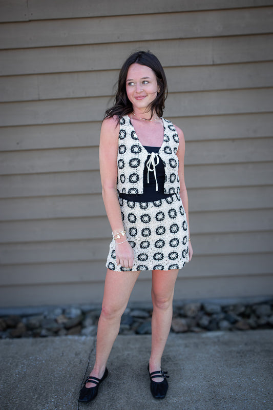 Woman wearing a patterned set standing against a beige wall.