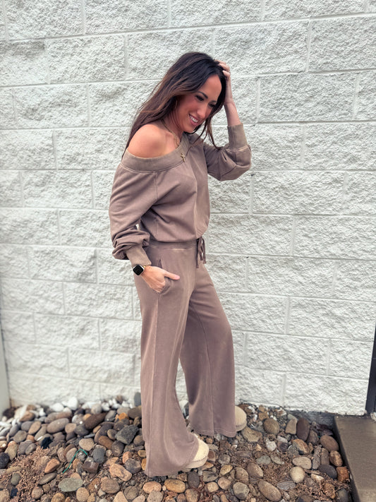 Brown jumpsuit worn off one shoulder