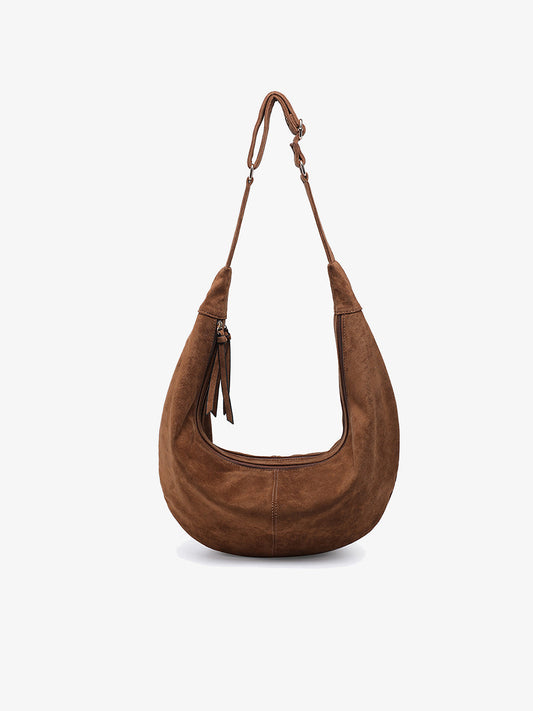 Brown suede hobo style shoulder bag with a crescent shape and adjustable strap with zipper closure