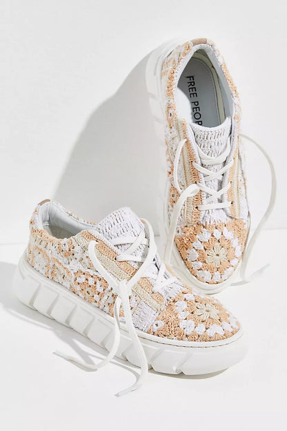 Pair of white and beige patterned sneakers on a light gray background