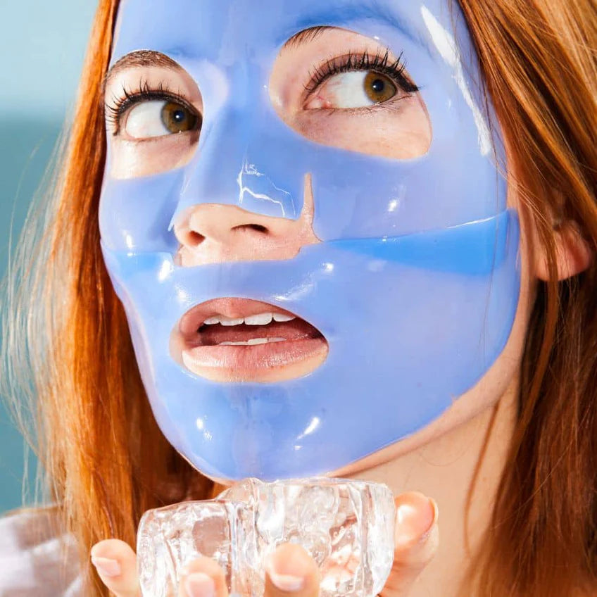 Woman wearing a blue face mask holding a glass of water against a light blue background