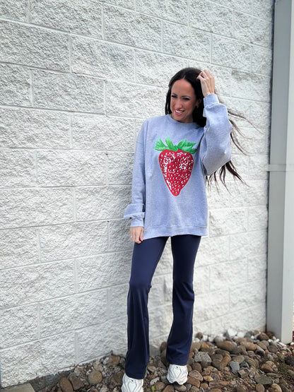 Gray sweatshirt with a strawberry design paired with navy flare leggings