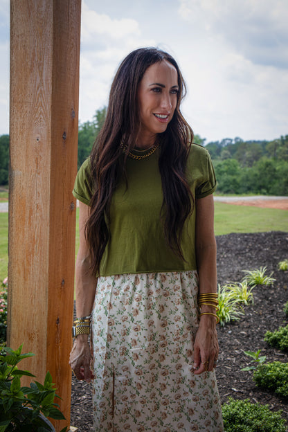 Woman wearing a green cropped tee and floral silk skirt outdoors
