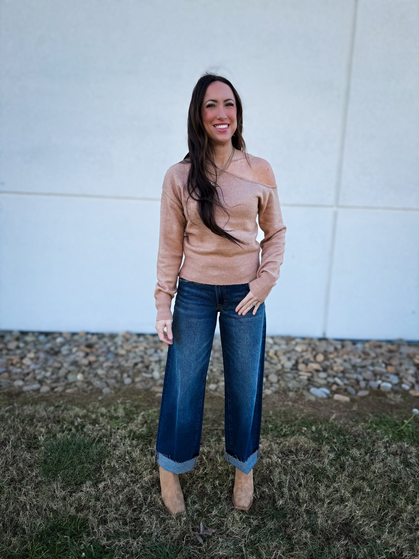 Woman wearing a beige off the shoulder sweater and blue jeans