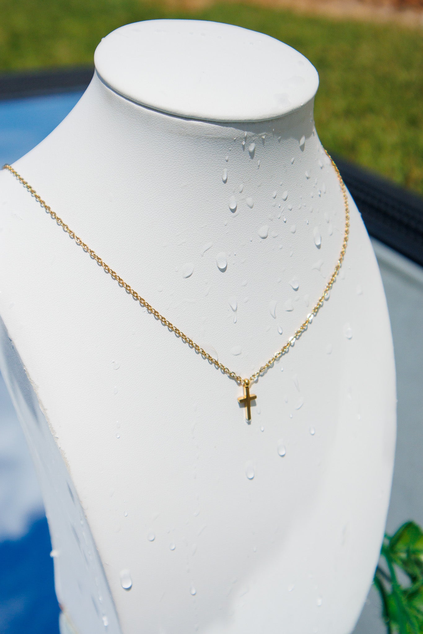 Gold necklace with a cross pendant on a mannequin bust. Waterproof & tarnish resistant. 