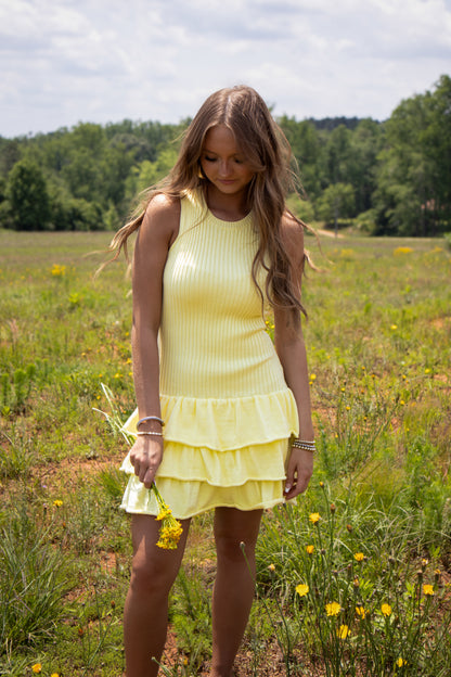 Woman in a yellow dress standing in a field of wildflowers
