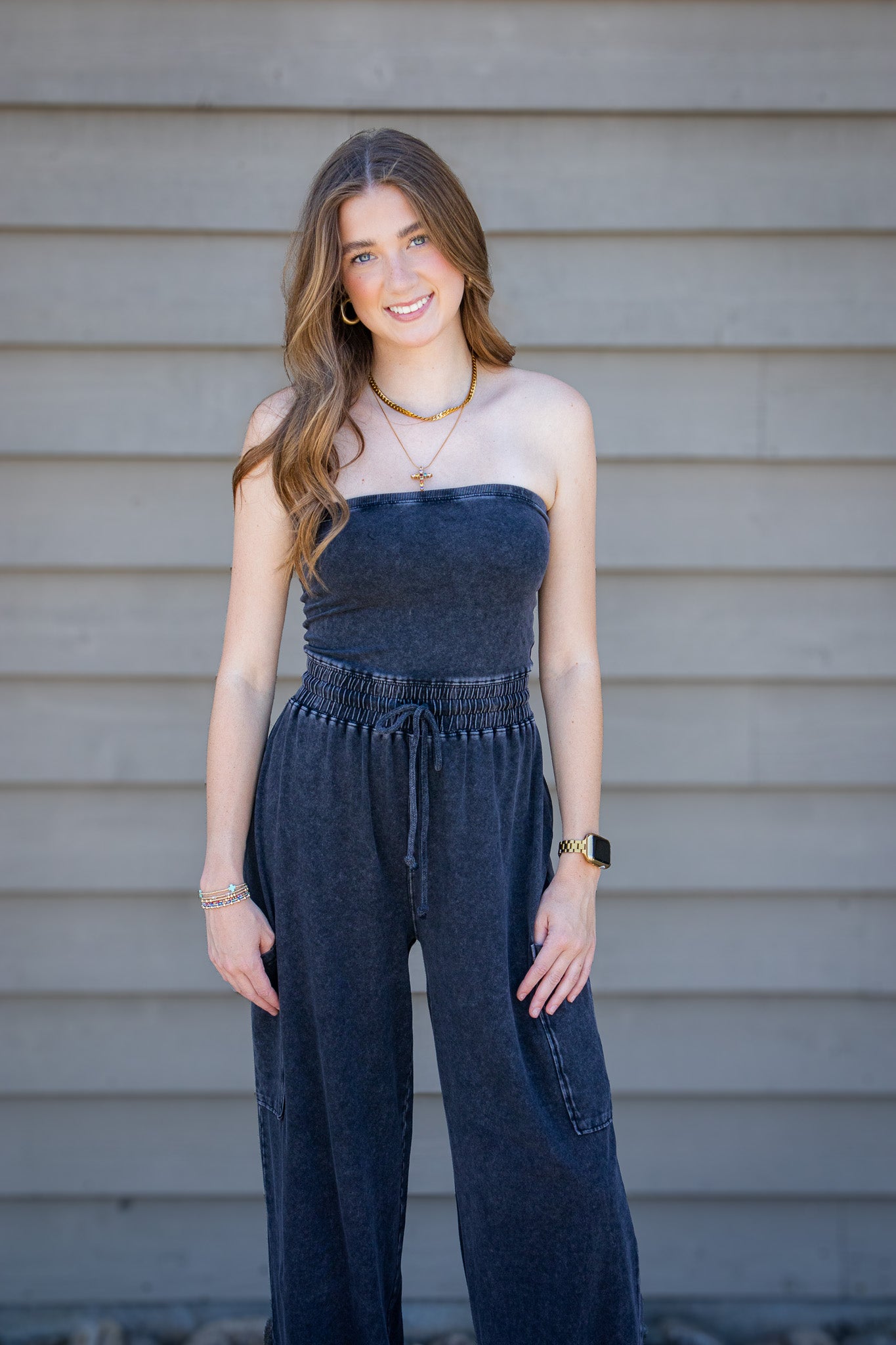 Woman wearing a denim jumpsuit standing against a neutral background