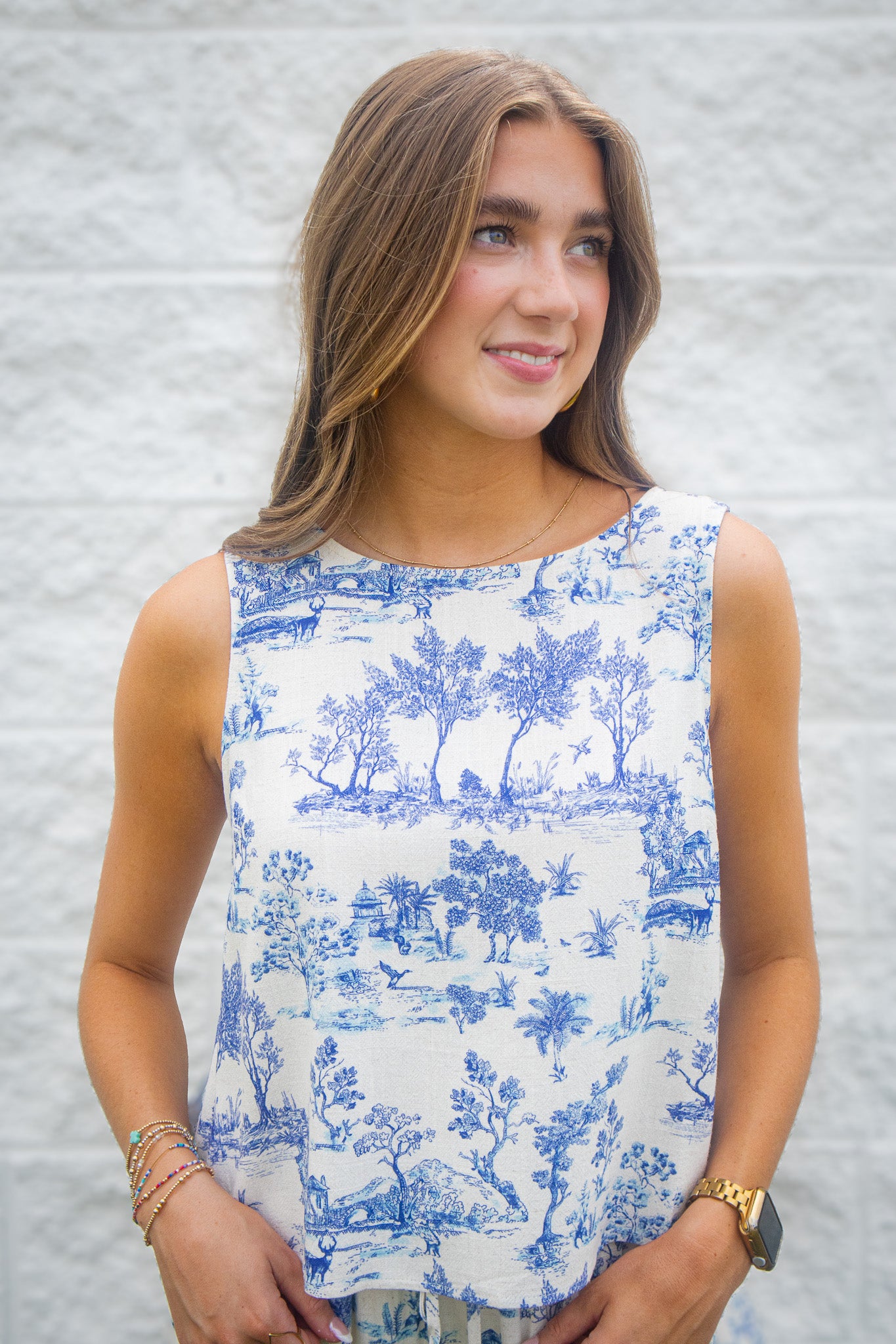 Woman wearing a blue and white patterned linen sleeveless top against a white background