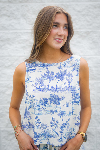 Woman wearing a blue and white patterned linen sleeveless top against a white background