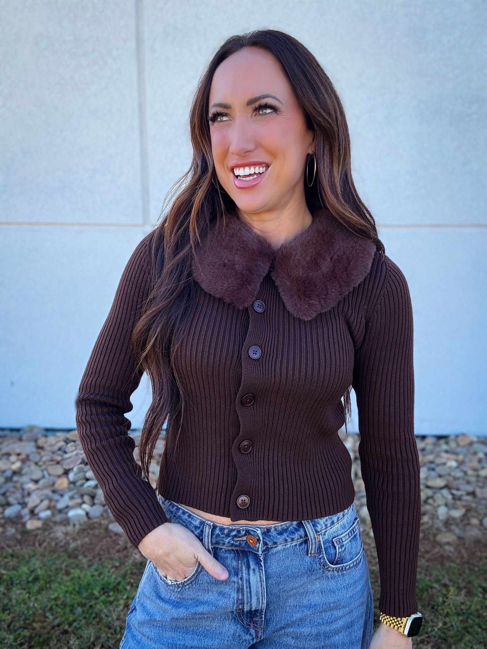 Woman wearing a brown ribbed button down sweater with a fur collar 
