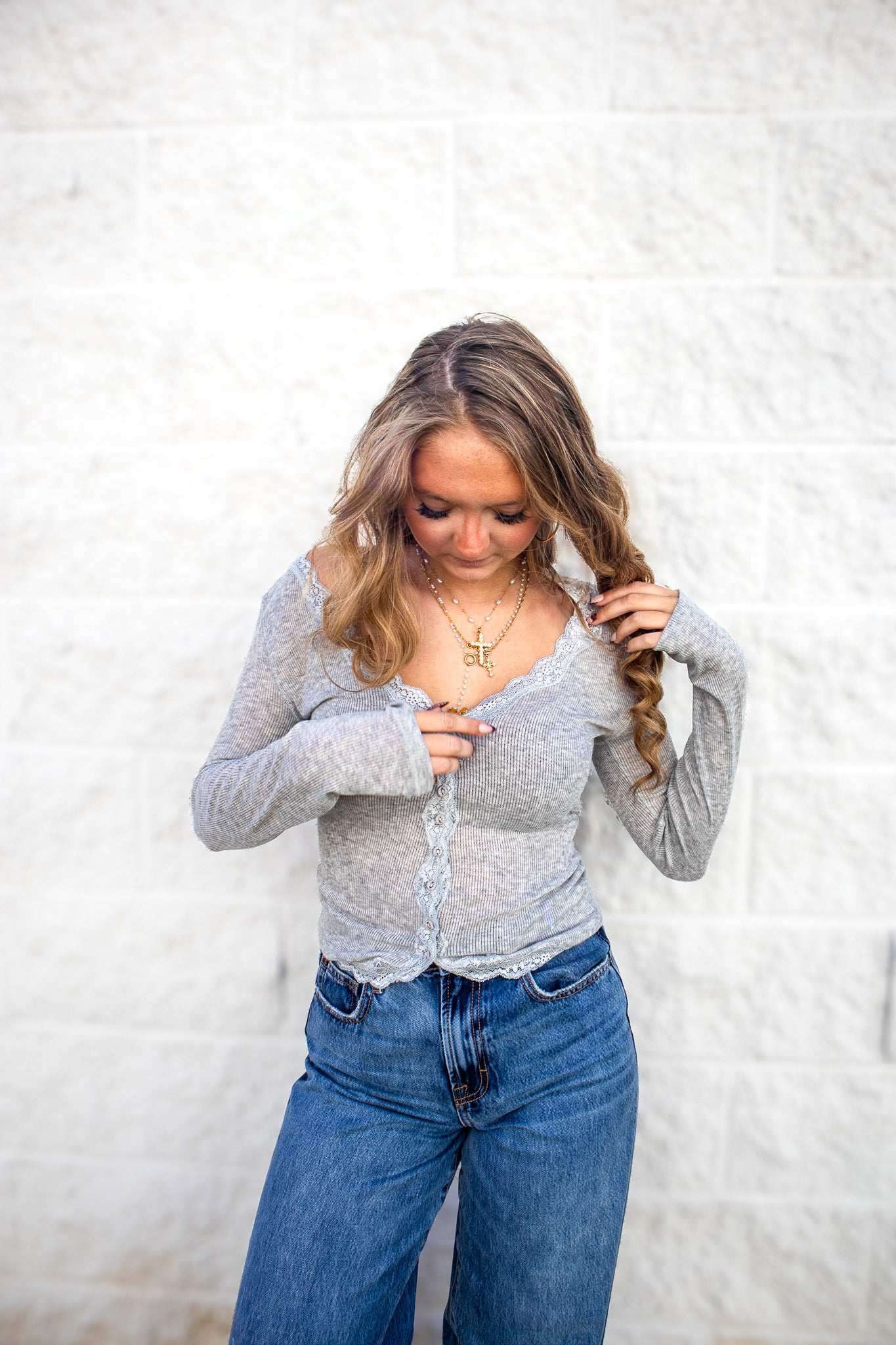 Woman wearing a gray ribbed long sleeve with buttons and lace detail. 