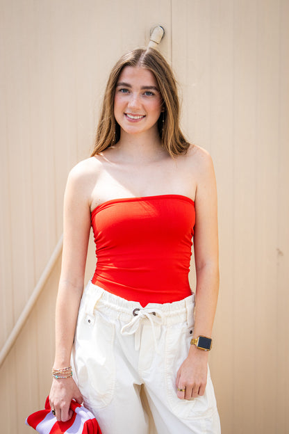 Red strapless tube top paired with white drawstring cargo pants for a cute summer outfit, Fourth of July style, vacation look, or red and white gameday outfit.