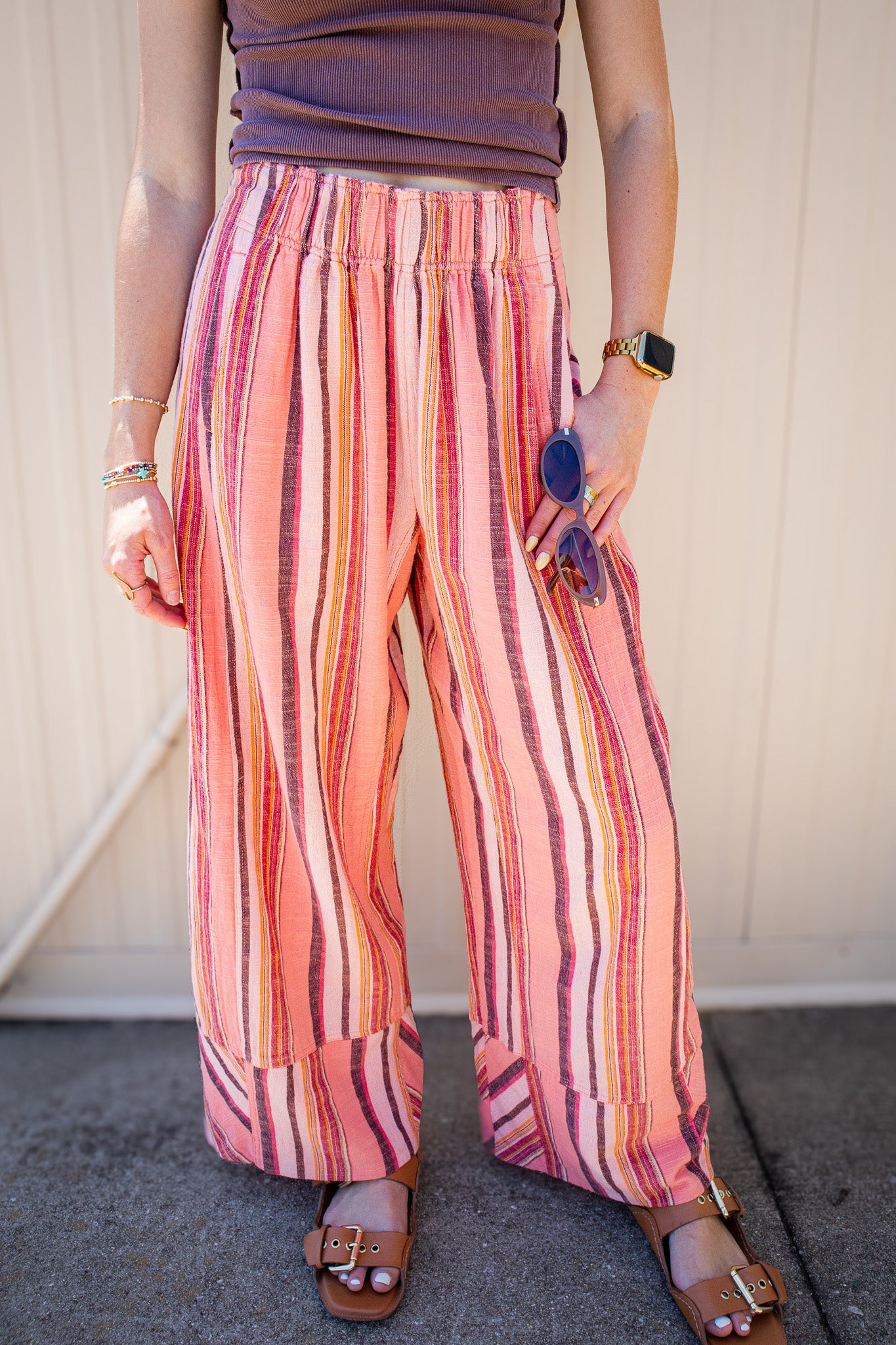 Coral striped wide leg pull-on pants styled with a fitted brown tank and sandals for a trendy summer boutique outfit, perfect for vacation, beach days, concerts, and casual weekend looks.