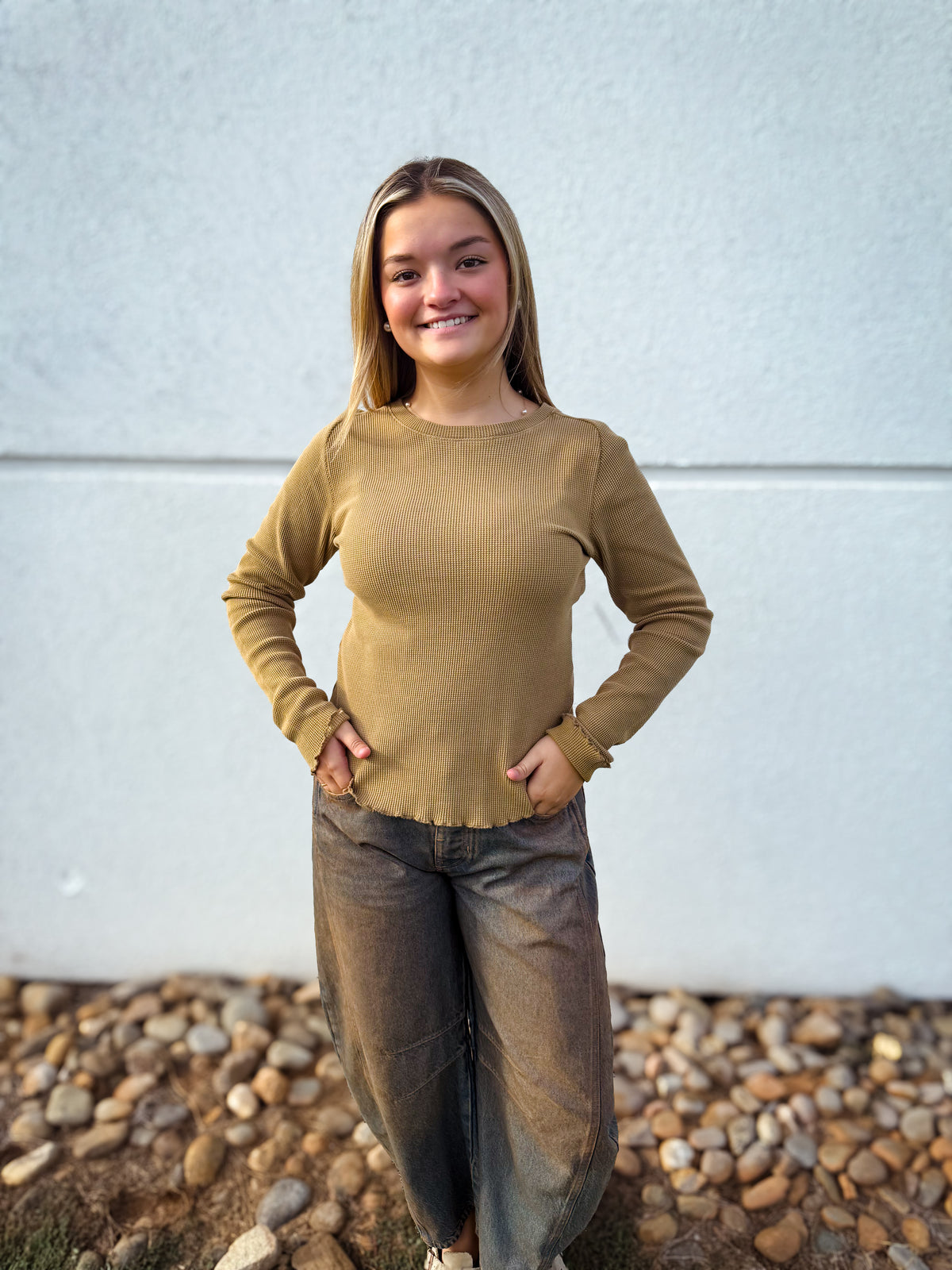 Model wearing a camel waffle knit long sleeve top with a crew neckline and lettuce-edge hem, styled with charcoal barrel leg jeans for a casual fall outfit.
