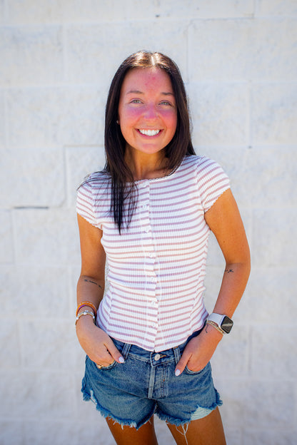 Woman wearing a striped shirt and denim shorts against a light background