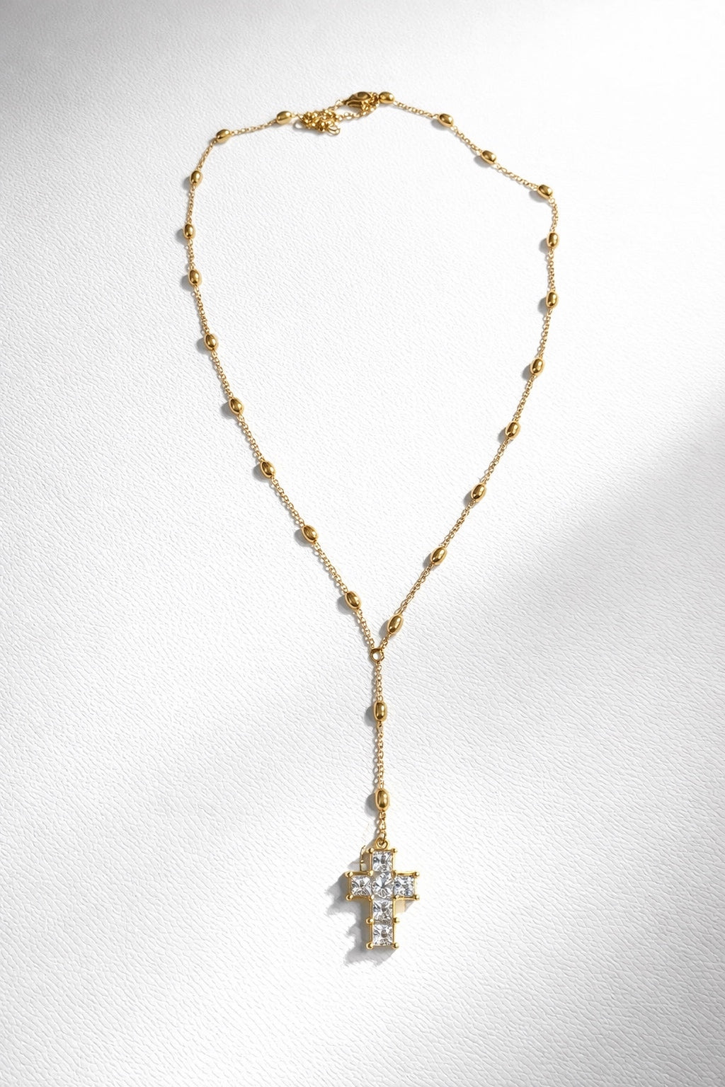 Trendy gold cross necklace with lariat chain design and diamond-like crystal pendant