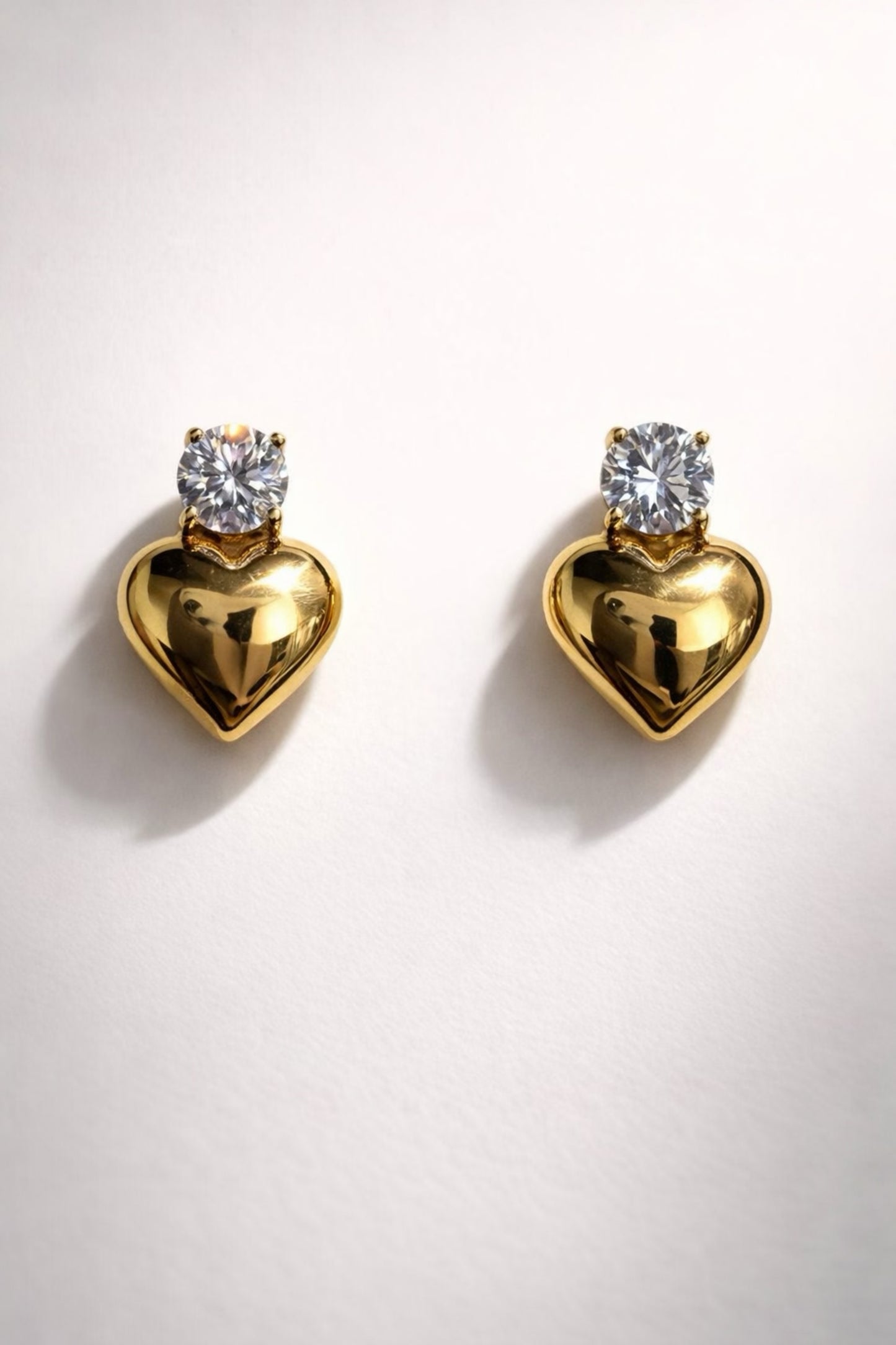 Gold heart-shaped stud earrings with crystal stud. 