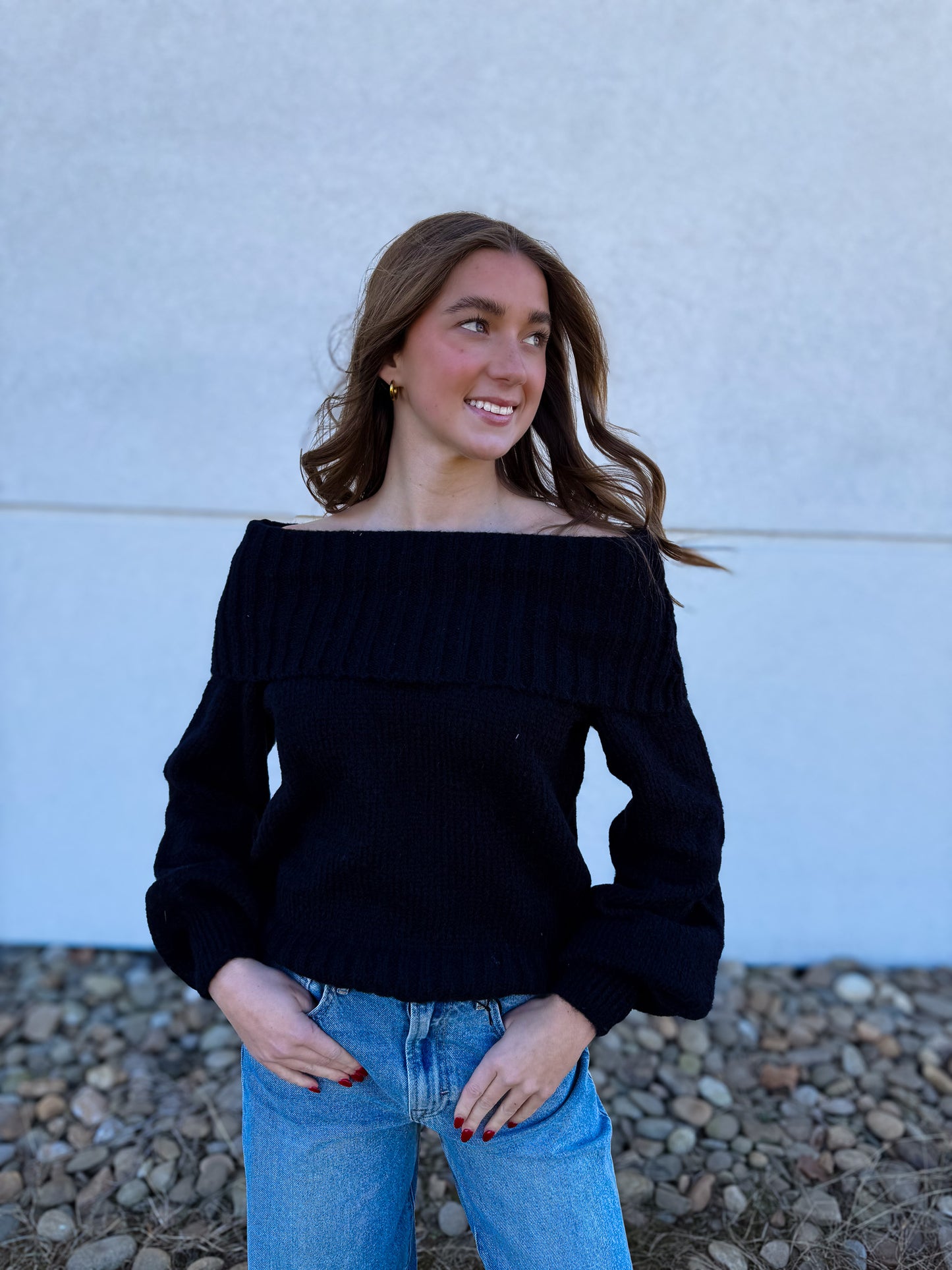 Woman wearing a black off-shoulder sweater and blue jeans