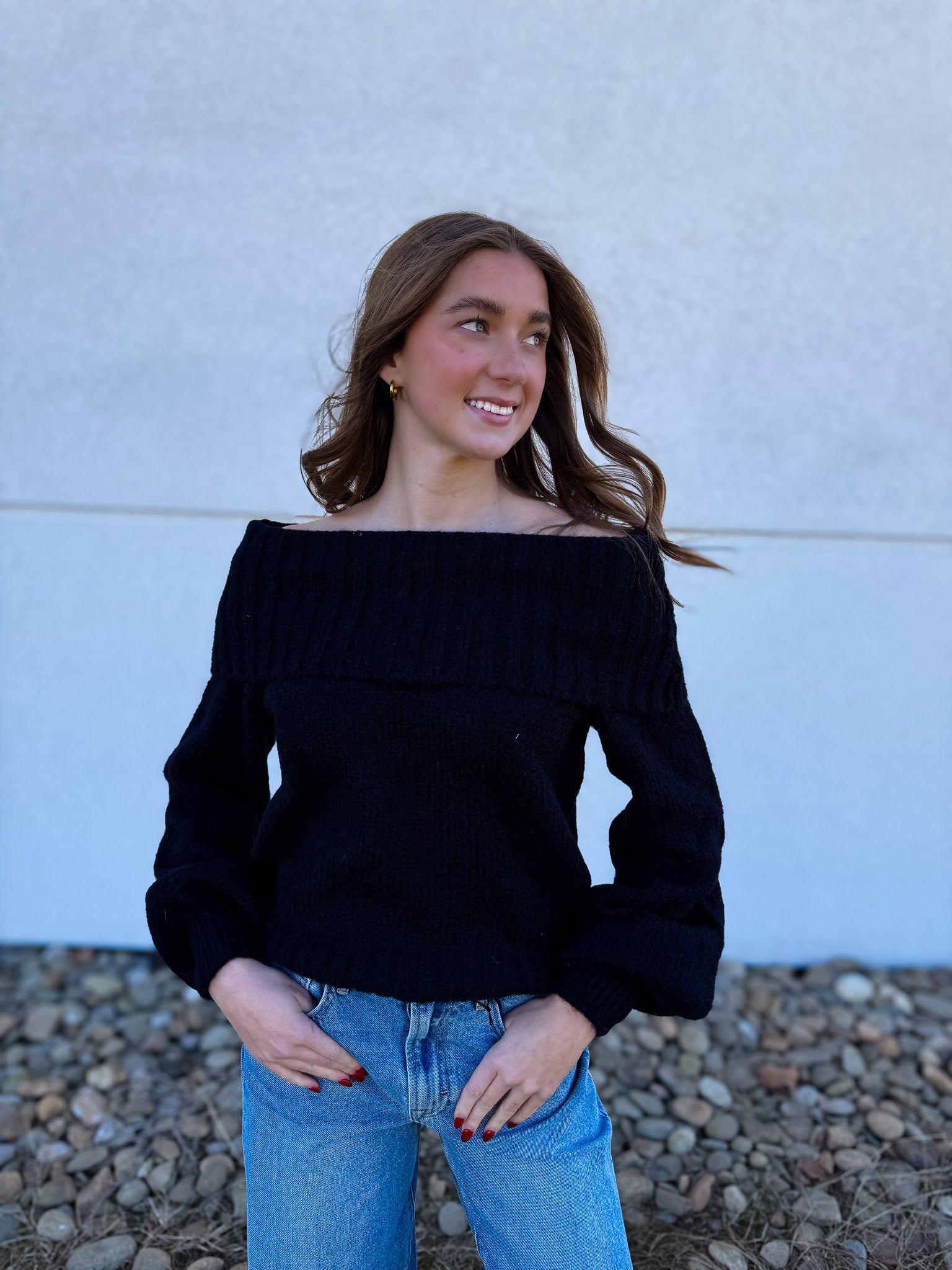 Woman wearing a black off-shoulder sweater and blue jeans