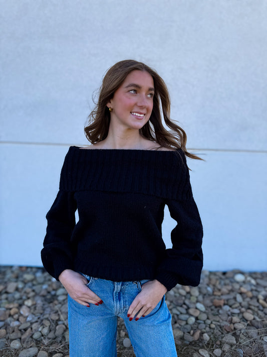 Woman wearing a black off-shoulder sweater and blue jeans