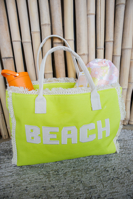 Bright green beach bag with 'BEACH' text, white handles, and a bamboo background.