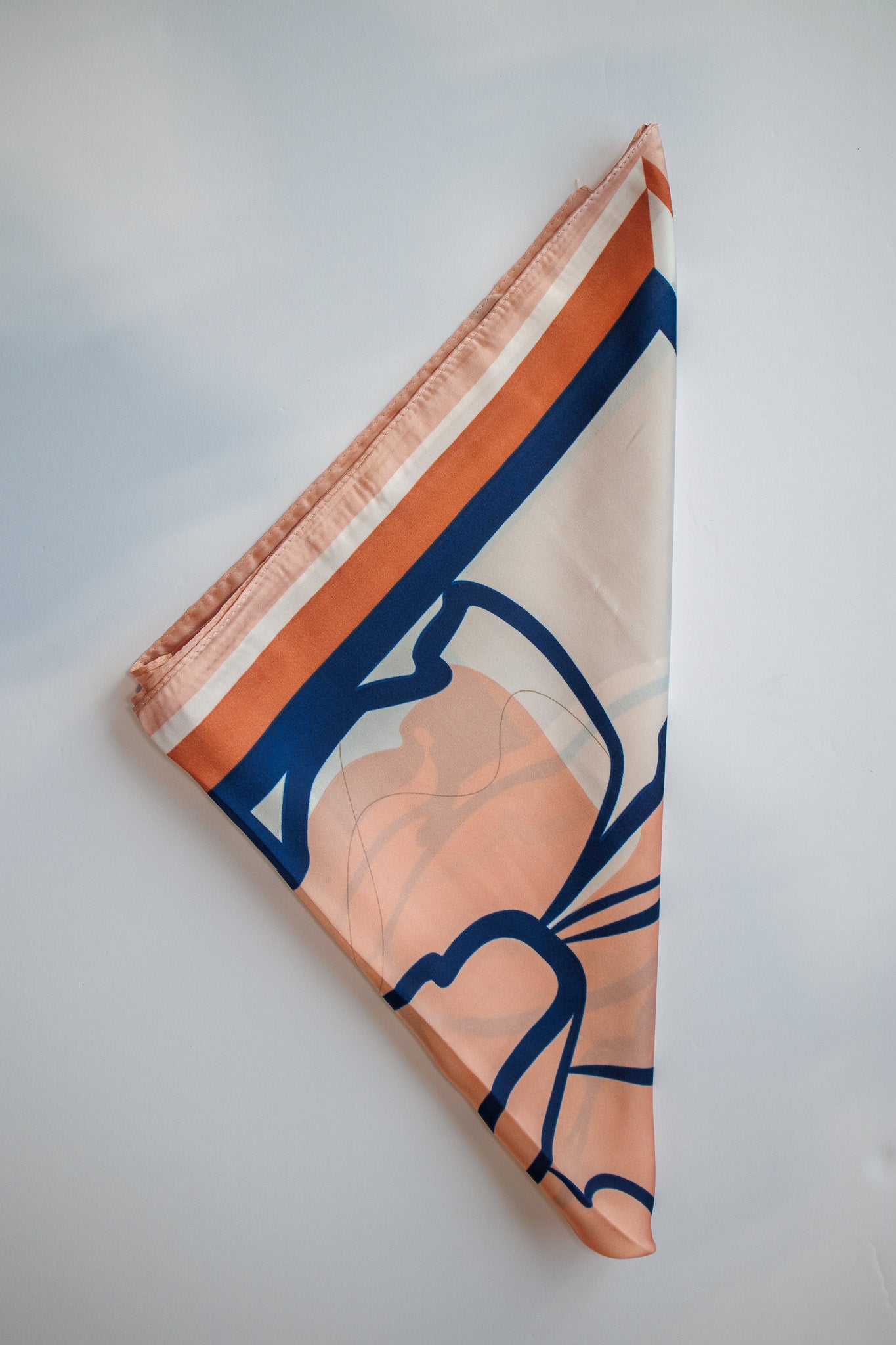 Folded fabric with orange and blue pattern on a light gray background
