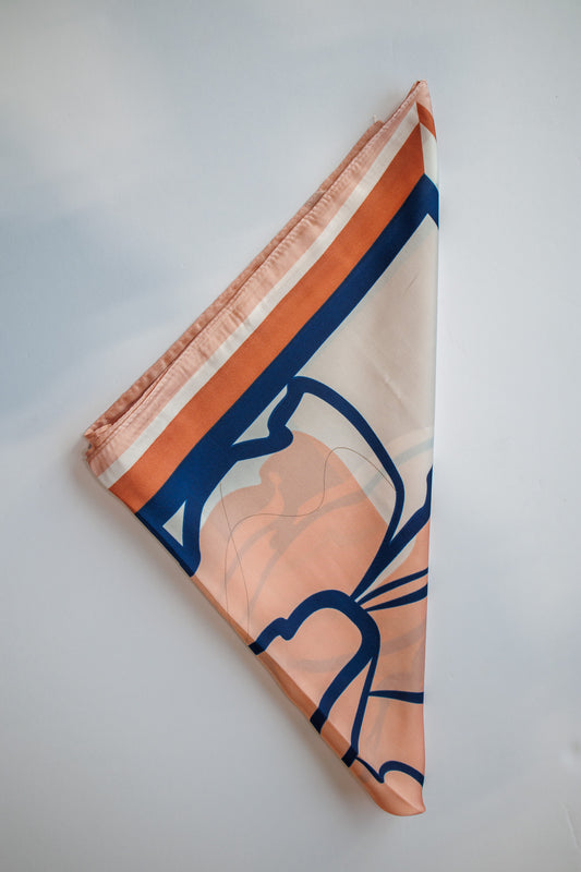Folded fabric with orange and blue pattern on a light gray background