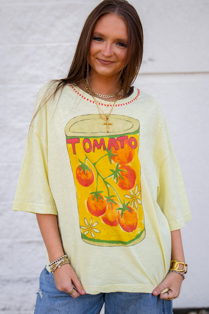 Woman wearing a light yellow t-shirt with a tomato graphic design and denim jeans against a white background