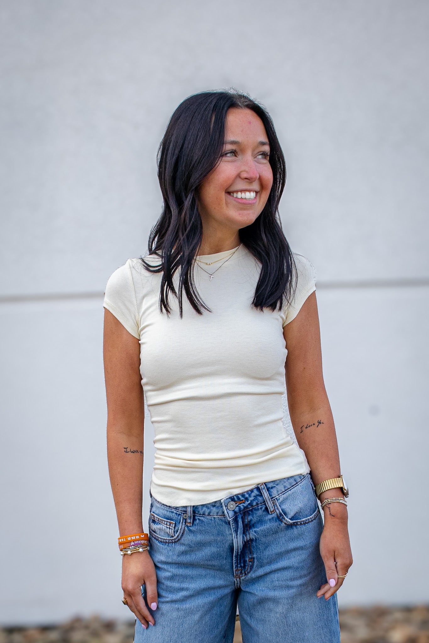 Woman wearing a white t-shirt and blue jeans against a plain background