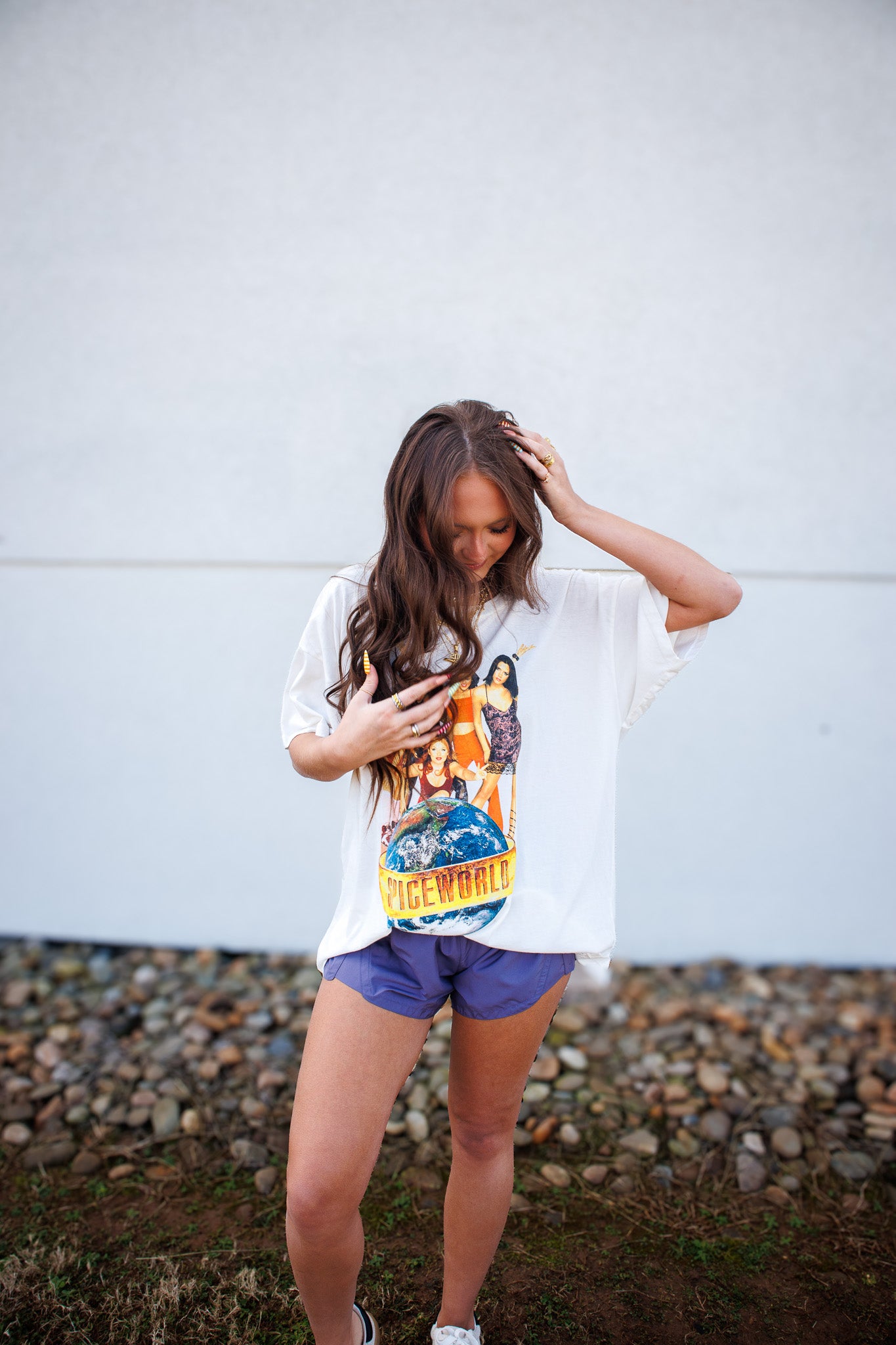 Person wearing a graphic t-shirt and purple athletic shorts against a white wall.
