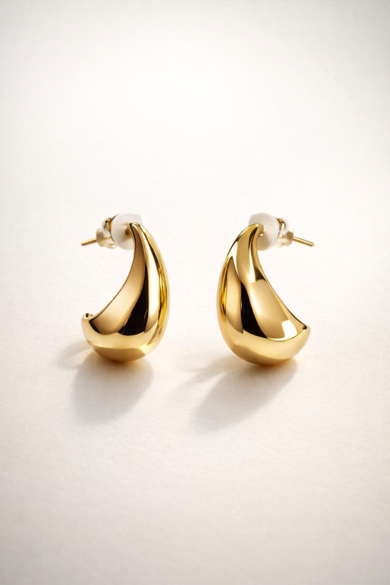 Gold teardrop stud earrings with a smooth, high-shine polished finish