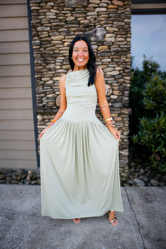 Woman in a light green dress standing in front of a stone wall.