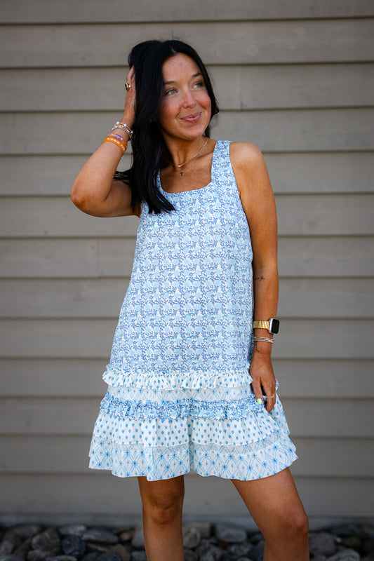 Woman wearing a light blue floral dress standing against a neutral background