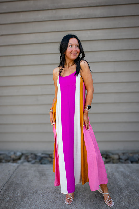 Woman wearing a colorful striped dress standing against a neutral background
