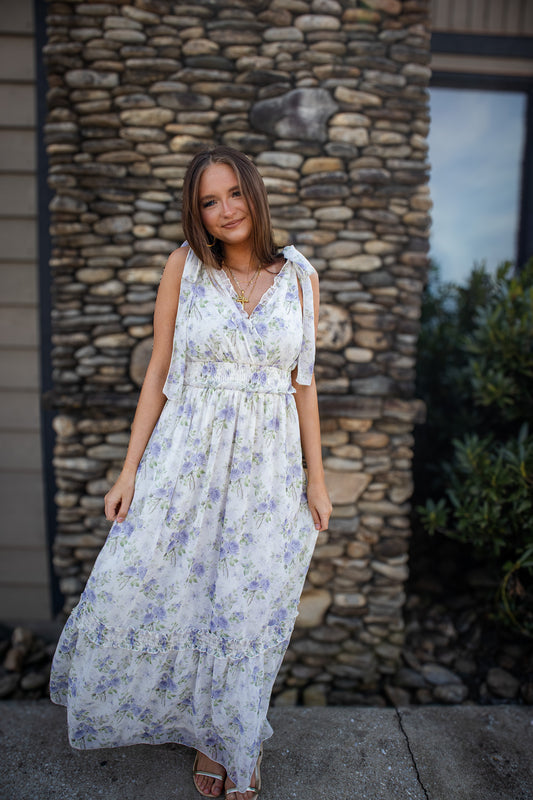 Woman in a floral dress standing in front of a stone wall