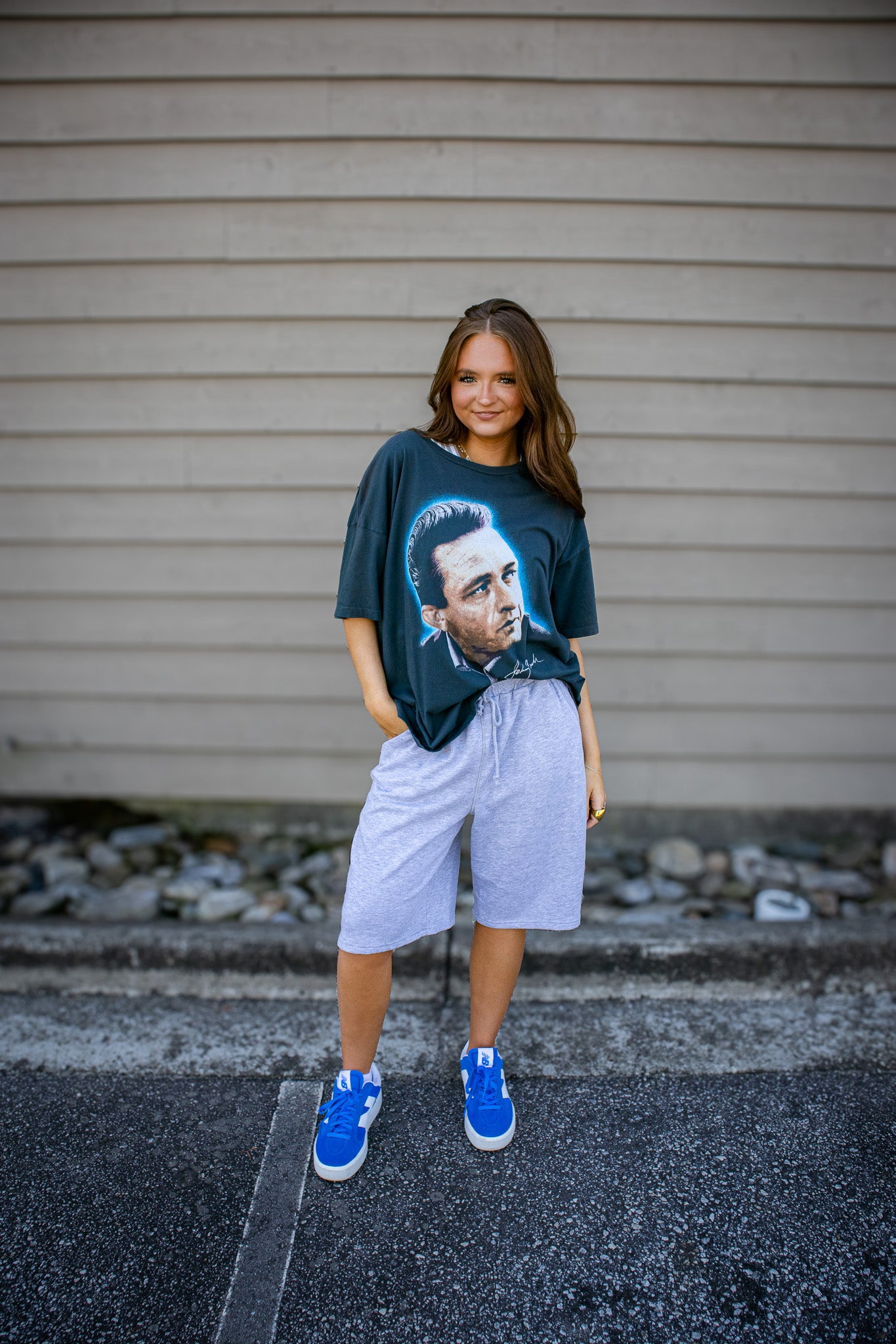 Person wearing a graphic t-shirt with a face design, standing against a plain wall.