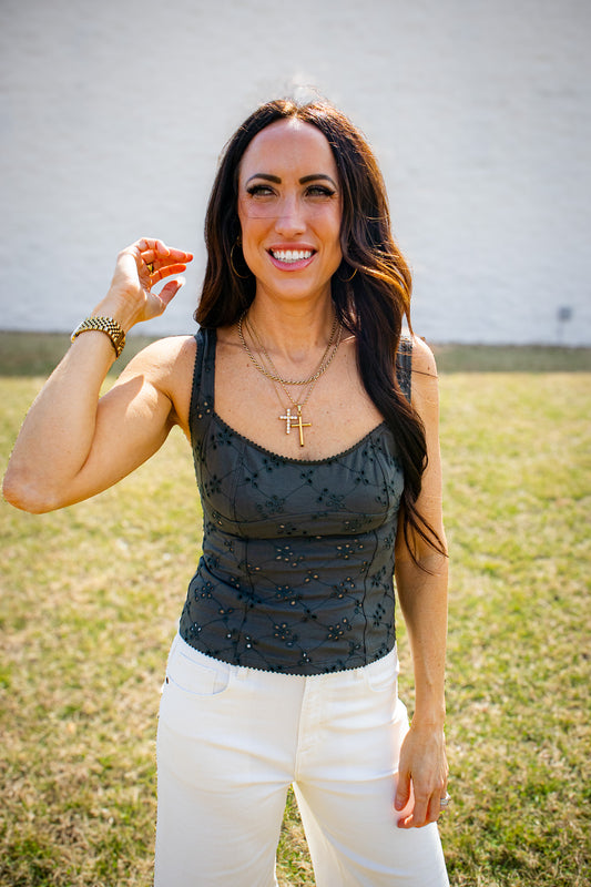 Woman wearing a green top with floral patterns and white pants outdoors.
