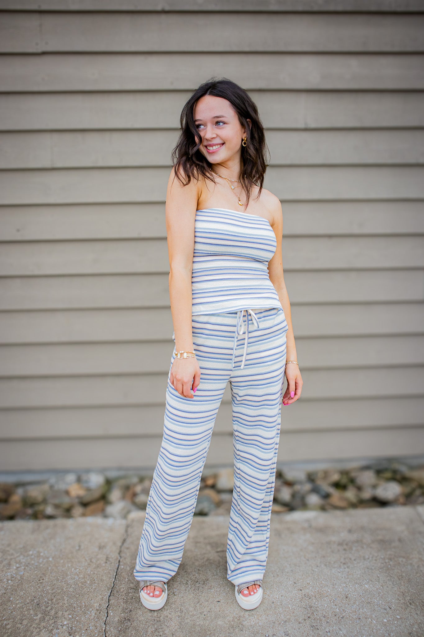 Woman wearing a striped set standing in front of a beige wall.
