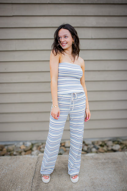Woman wearing a striped set standing in front of a beige wall.