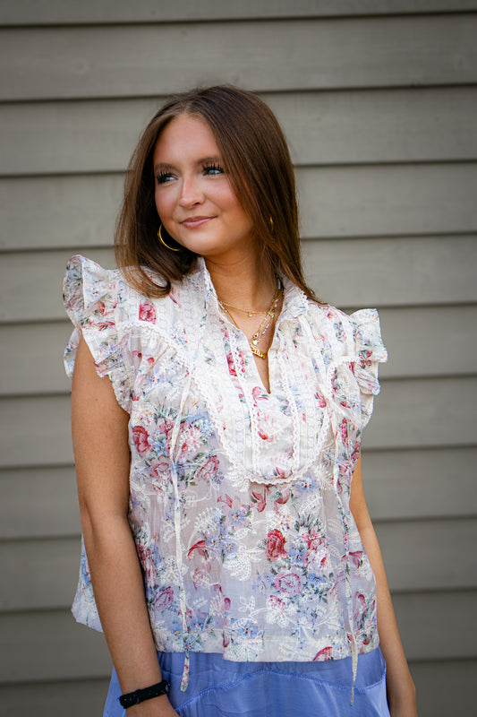 Woman wearing a floral blouse standing against a neutral background