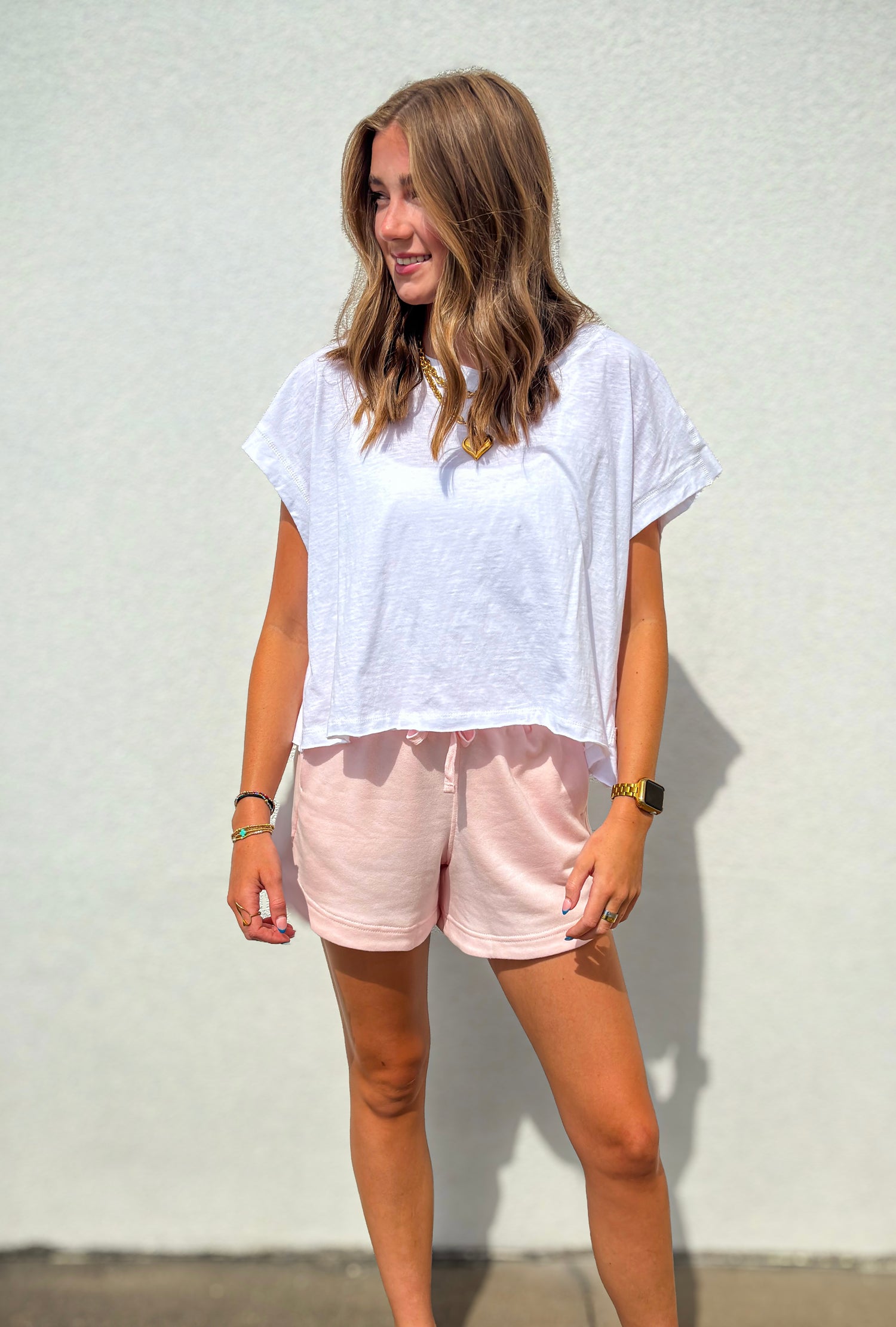 Woman wearing a white t-shirt and pink shorts against a plain background