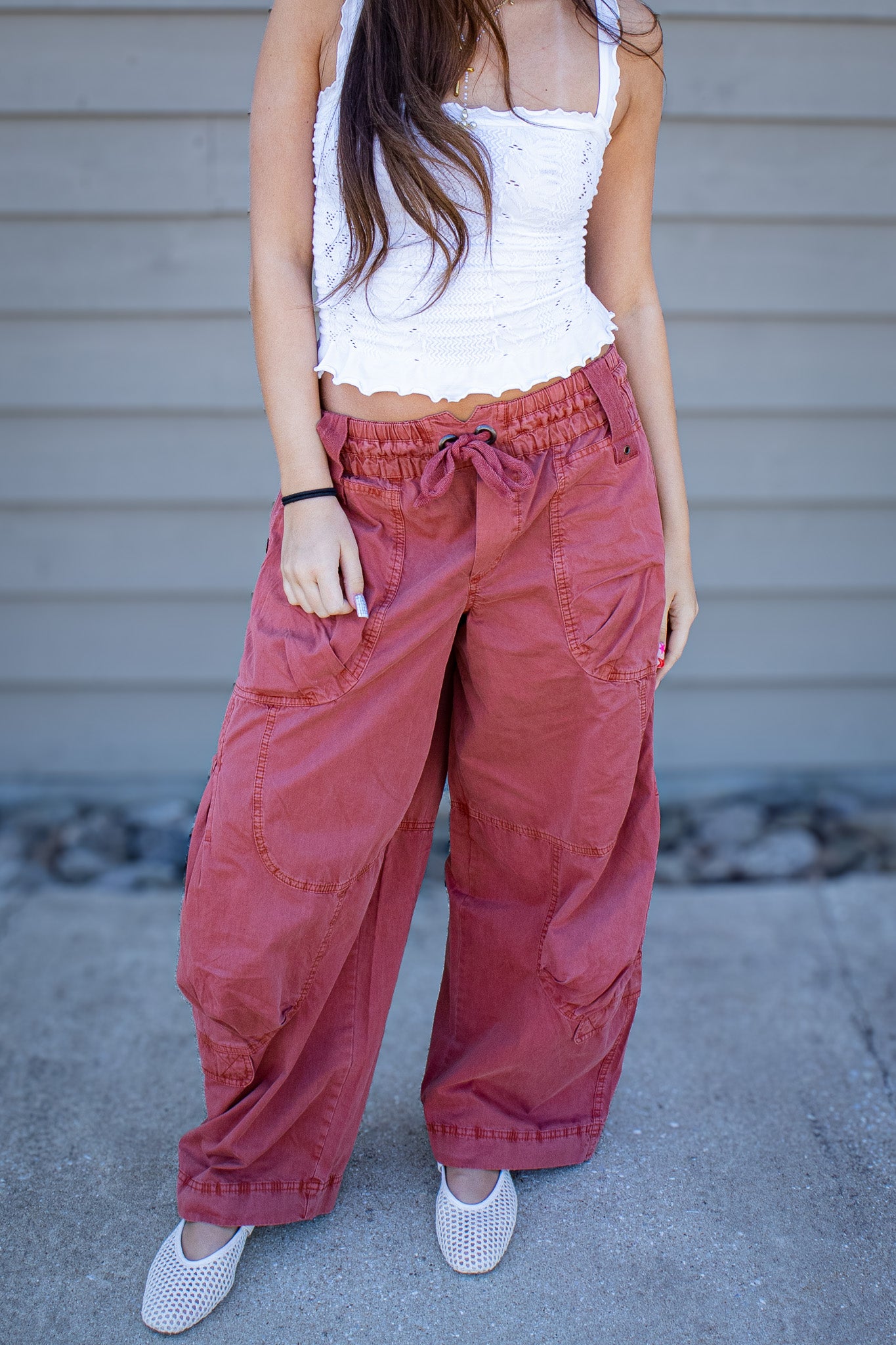 Rust wide leg cargo pants with oversized pockets and drawstring waist, styled with a white lace trim fitted tank top for a trendy casual boutique outfit outdoors