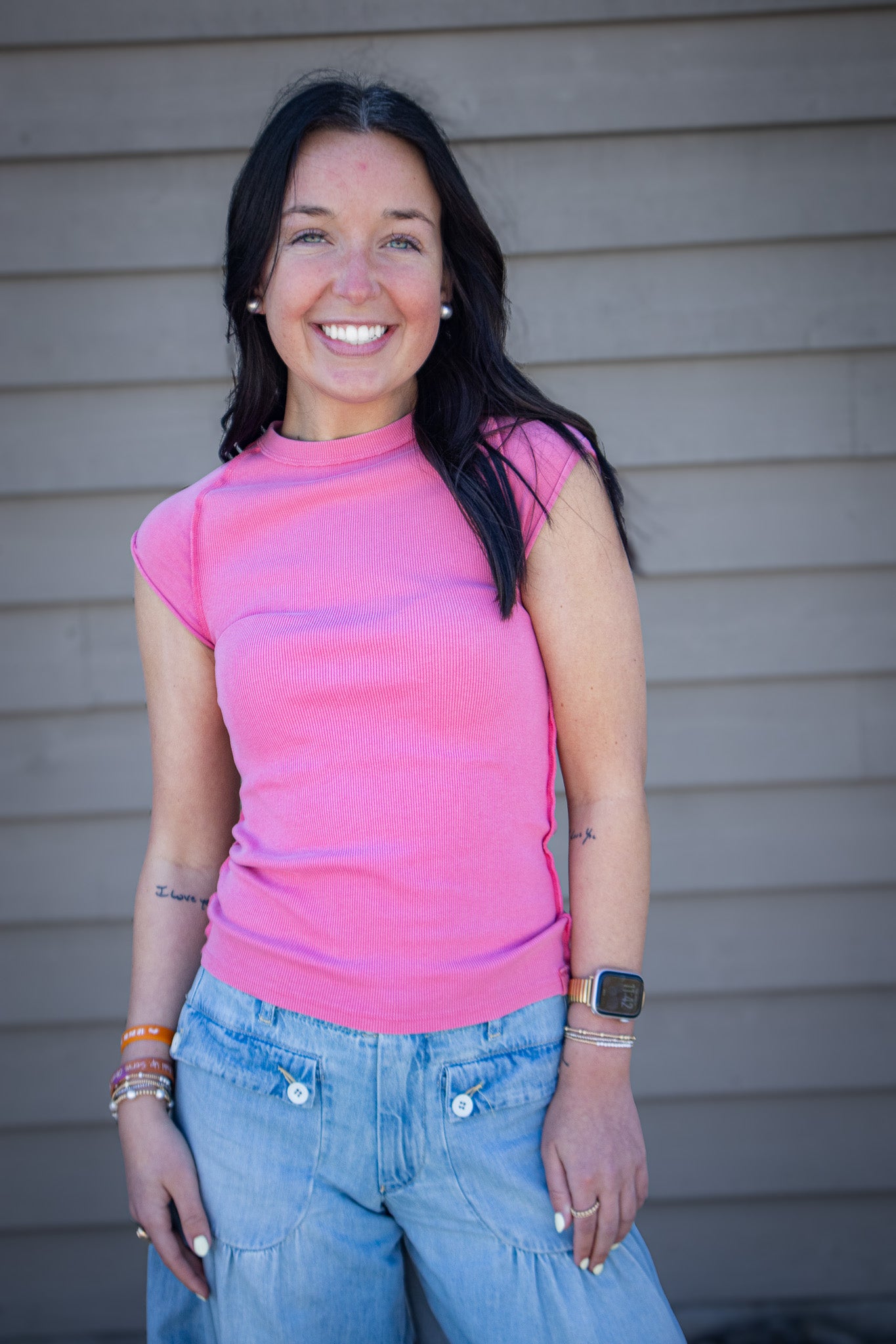 Woman wearing bright pink fitted cap sleeve top with light wash wide leg jeans, casual trendy outfit styled for everyday wear, boutique fashion look outdoors