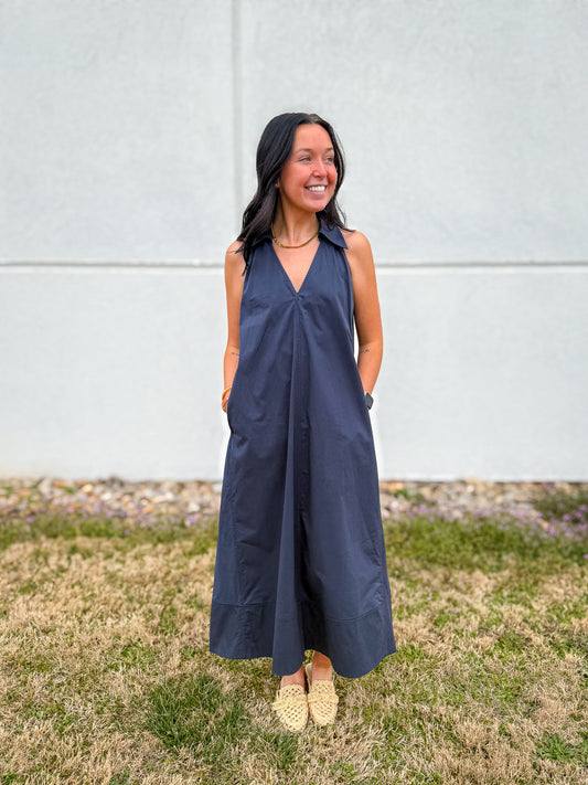 Navy sleeveless maxi dress with a relaxed flowy silhouette, v-neckline, and collar detail, styled with woven neutral flats and gold jewelry for a polished coastal look.