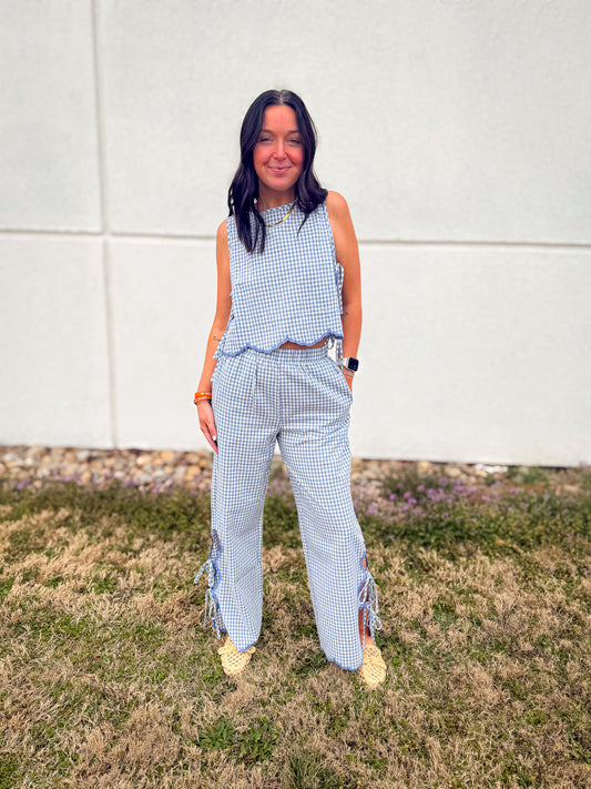 Person wearing a blue checkered outfit standing on grass with a white wall background