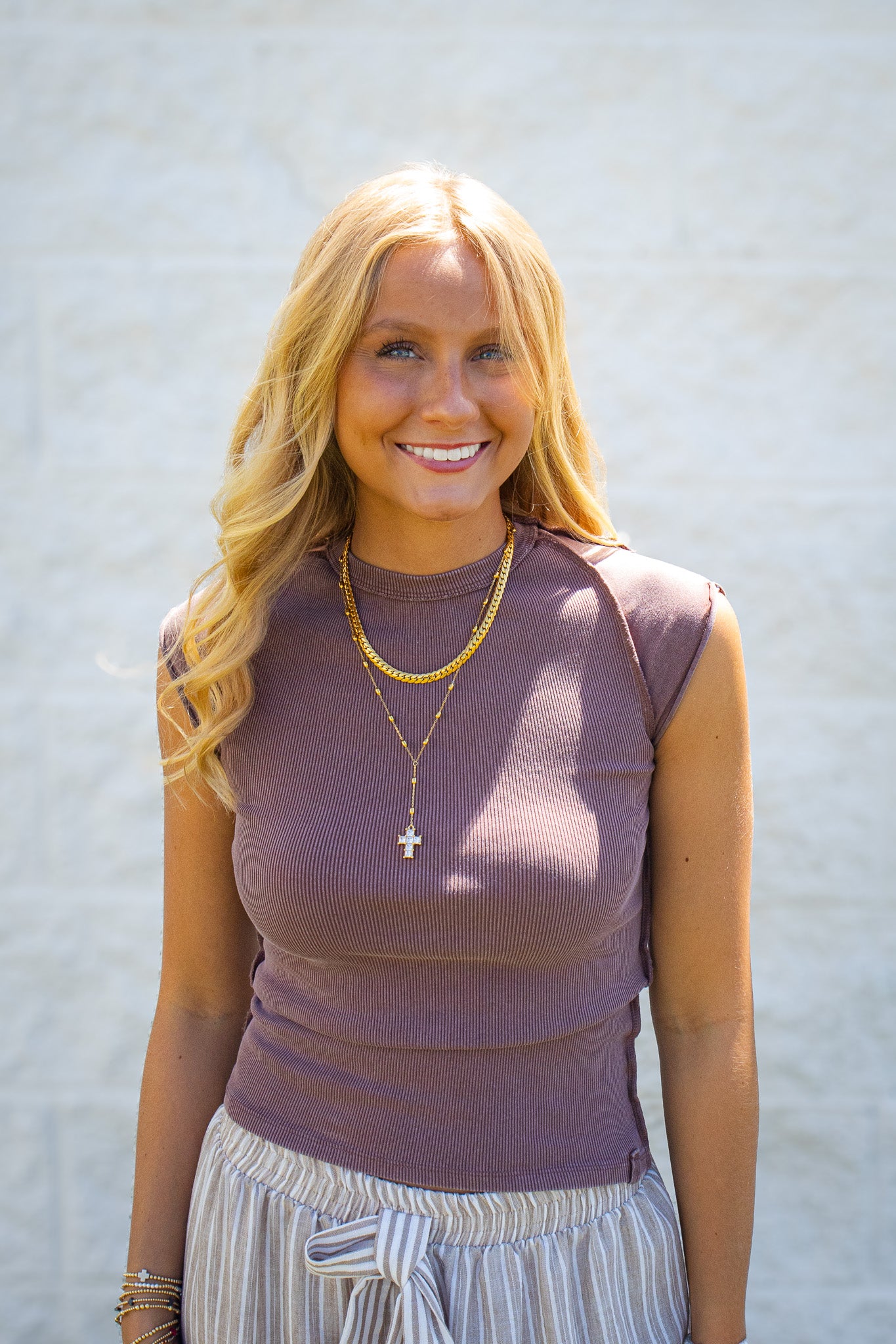 Brown ribbed sleeveless fitted top with a crew neckline, flattering stretch fit, and elevated everyday style, paired with neutral striped drawstring pants and layered gold jewelry for an effortless summer boutique outfit.