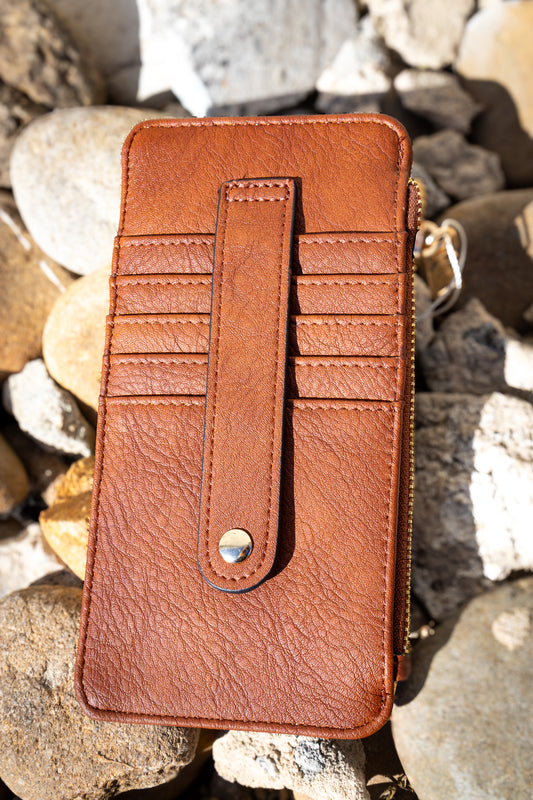 Brown leather wallet with card slots on a rocky surface