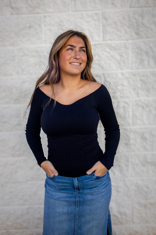 Woman wearing a black ribbed stretchy top and blue jean skirt 